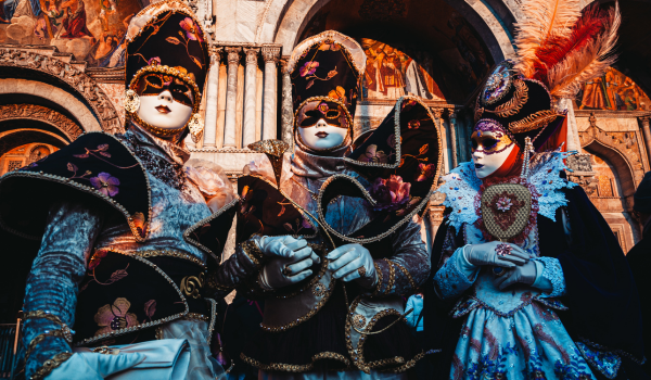 Three people wearing Italian carnival masks and outfits