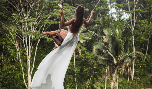 Young lady in a white dress on a Jungle swing in Ubud